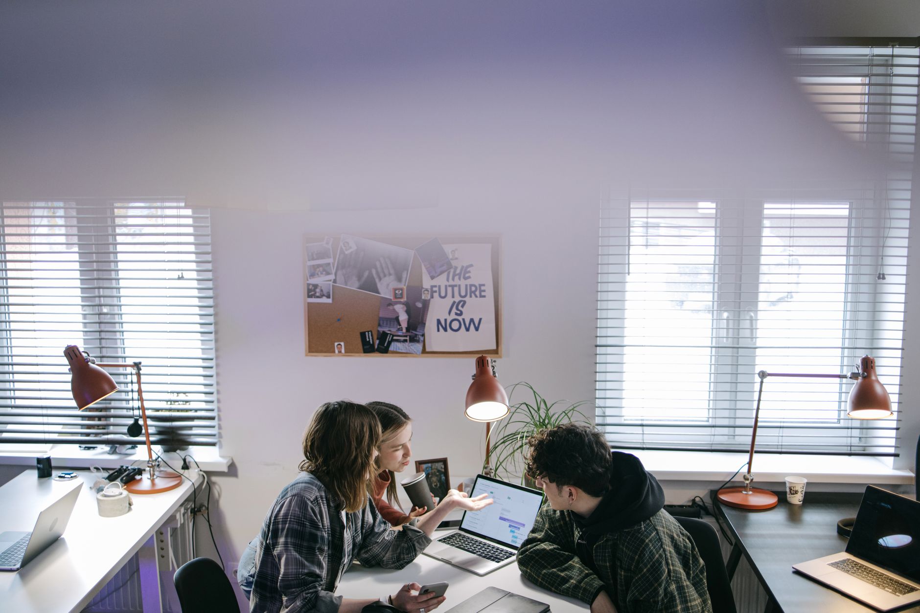 A group of people discussing ideas around laptops in a bright, modern office space — illustrating: Tampa IT Managed Services Comparison: Uptime, Support & Pricing for Central Florida Businesses (2025)